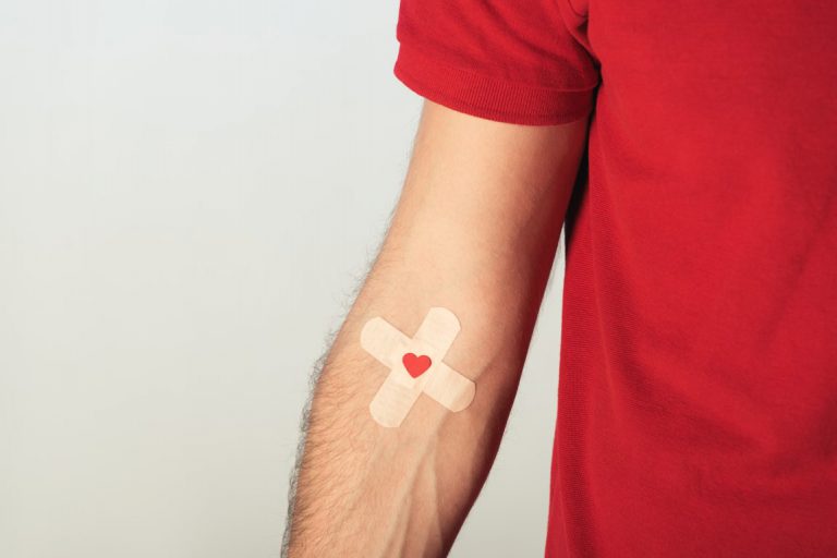 Partial View Of Patient In Red T Shirt With Plasters On Grey Background, Blood Donation Concept